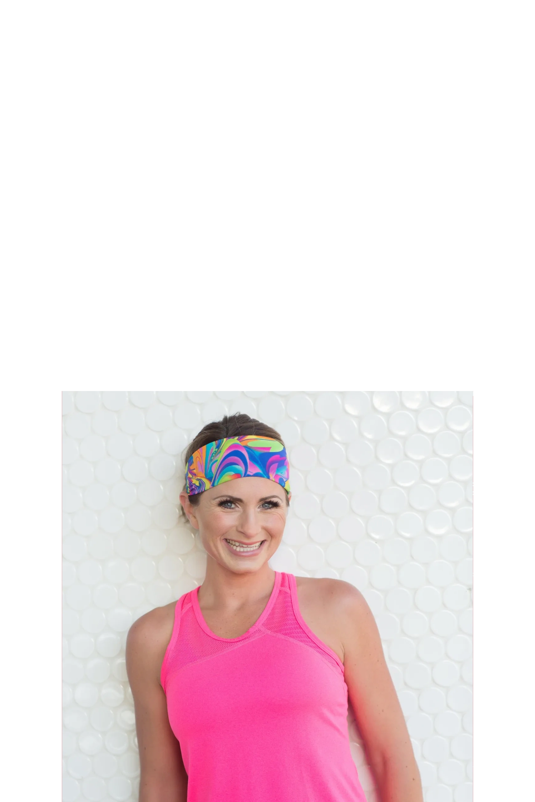 Smiling woman in a bright pink tank top and colorful headband.