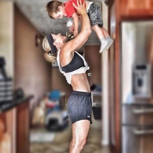 A woman lifts a smiling child in a home setting.