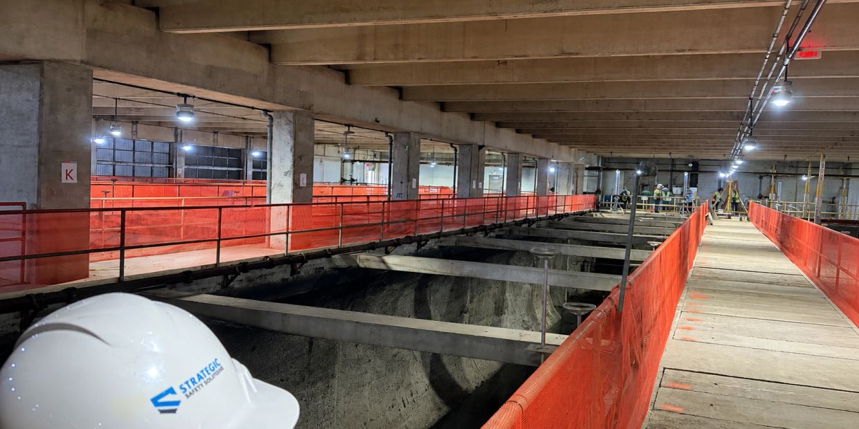 Construction site with safety barriers and workers in an indoor setting.