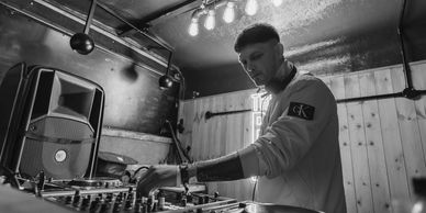 Image of man inside the horse box trailer, DJing using a controller with speaker in the background.