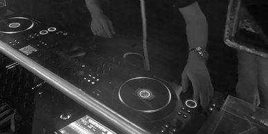 Image of man wearing headphones and DJing on a controller in a bar.