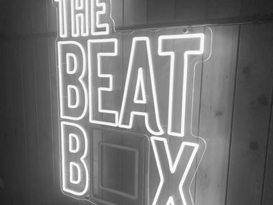 Image of The Beat Box neon sign in yellow and purple. The O of BOX is purple, the rest yellow.