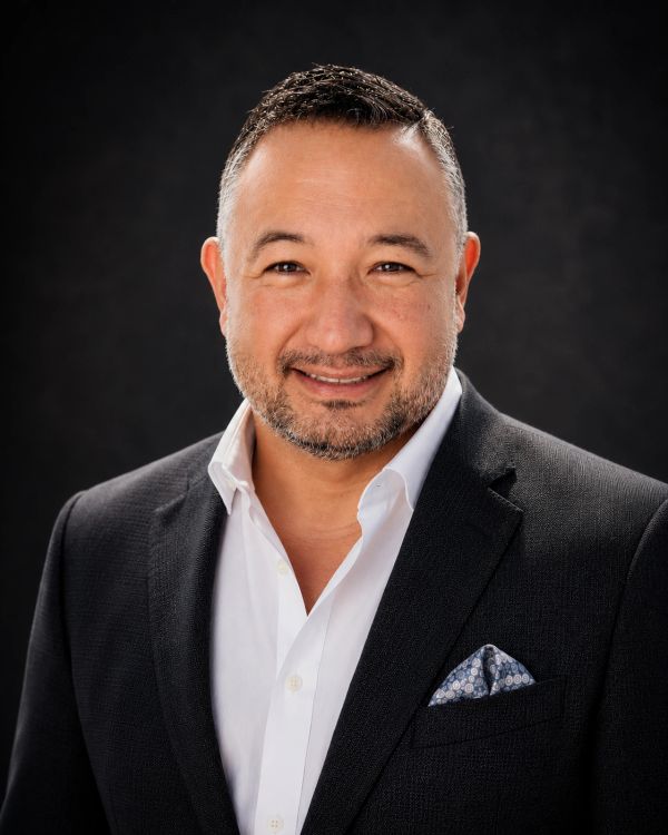 Smiling man in a black suit and white shirt.