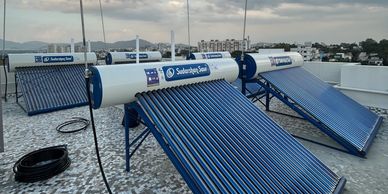 Solar water heaters installed on a rooftop under cloudy sky.