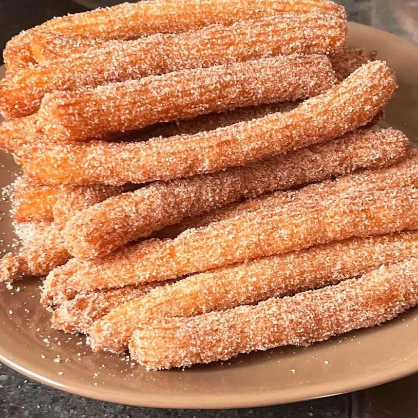 A plate of sugar-coated churros stacked neatly.