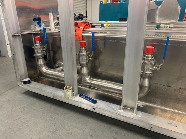 Industrial piping system with valves inside a metallic frame.