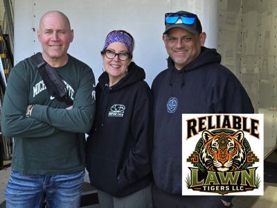 Three people smiling, dressed casually, with a Reliable Lawn Tigers LLC logo.