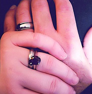Two hands with rings, one featuring a black gemstone.