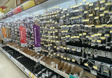 Hardware store aisle with hooks, hinges, and security hardware on display.