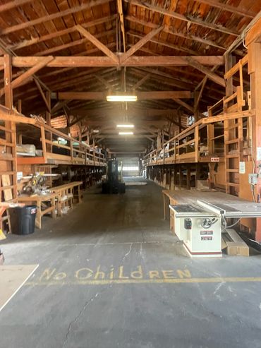 Interior of a large woodworking workshop with high wooden beams and tools.