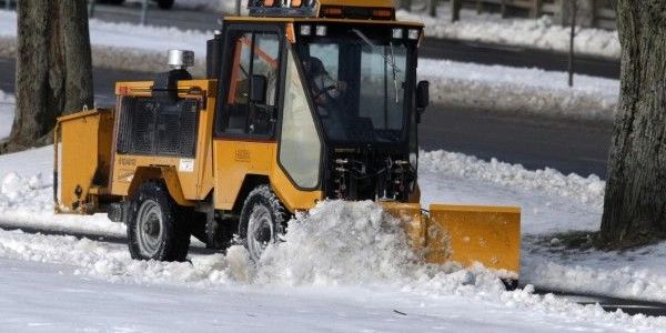 A utility vehicle clearing a snowy sidewalk in Surrey as part of a detailed snow removal contract.
