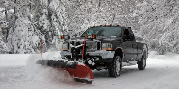 A pickup truck with a plow attachment providing 24/7 snow removal service in Surrey for driveways.