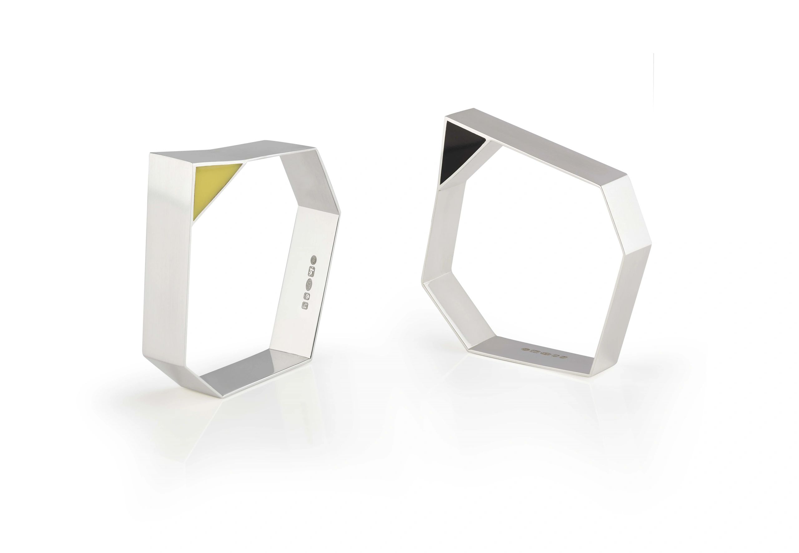 Two geometrical bangles, one with yellow and the other with black perspex decoration.