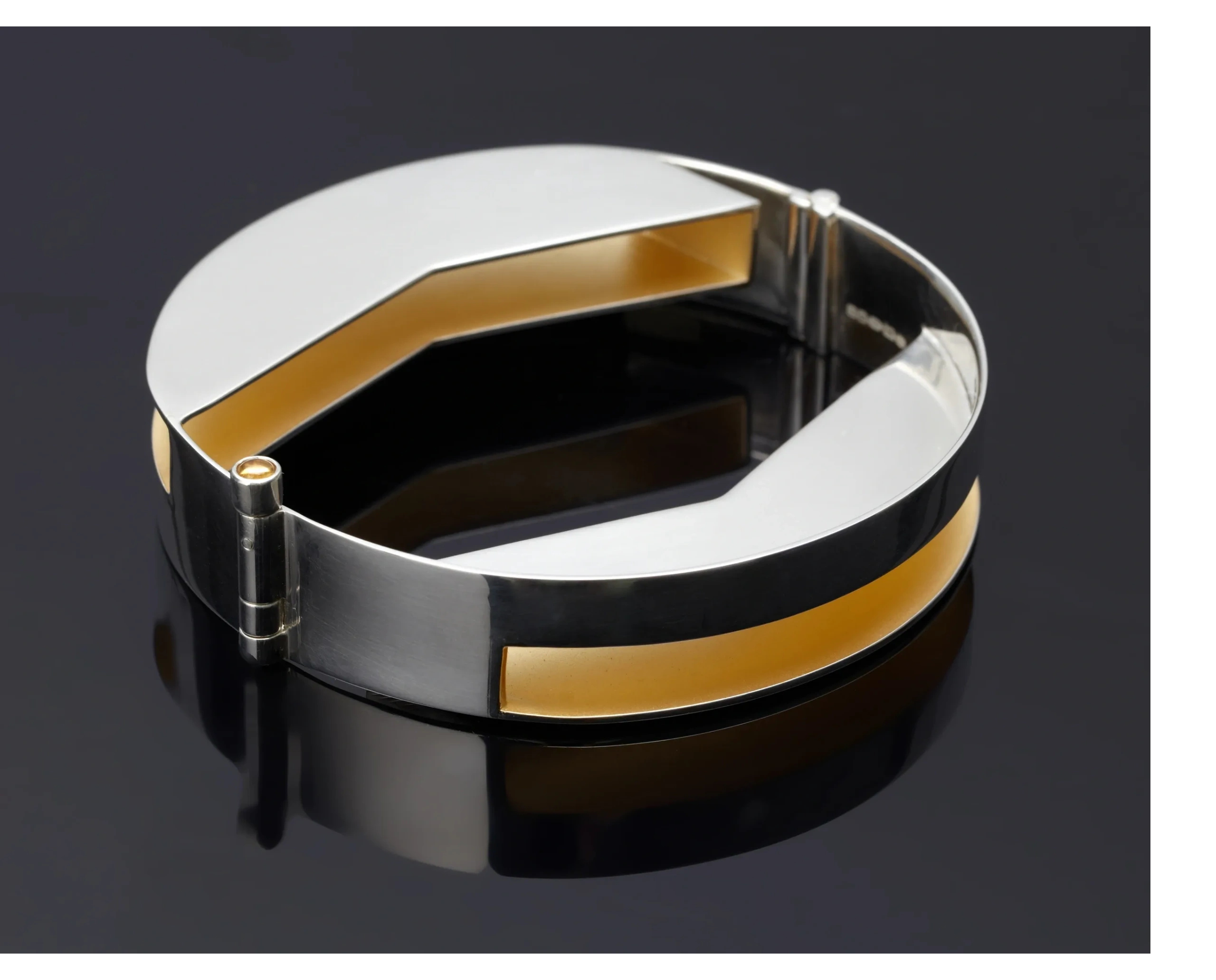 a hinged silver bangle with the interior gold plated in 22ct yellow gold.