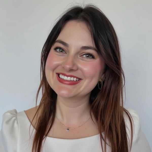 Smiling woman with long brown hair in white top.