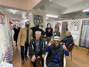 a group of hanuman charity volunteers at an elderly care come visit, smiling with elderly people