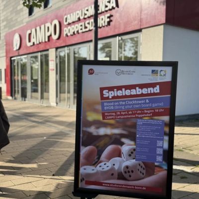 Werbetafel für einen Spieleabend vor einem Gebäude.