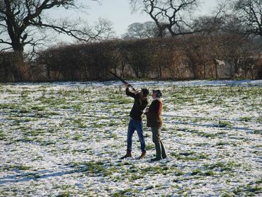 Man firing a shotgun under expert supervision with specialist game shooting guidance