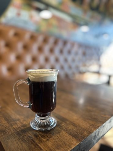 A dark cocktail in a short glass on a booth's table