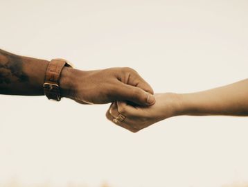 Two hands gently holding each other, symbolizing connection and support.
