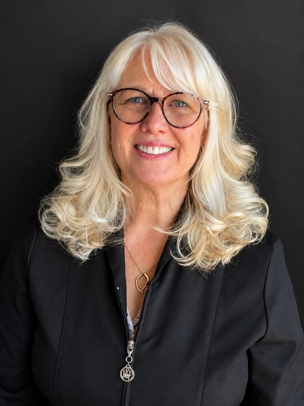 Smiling woman with blonde hair and glasses.