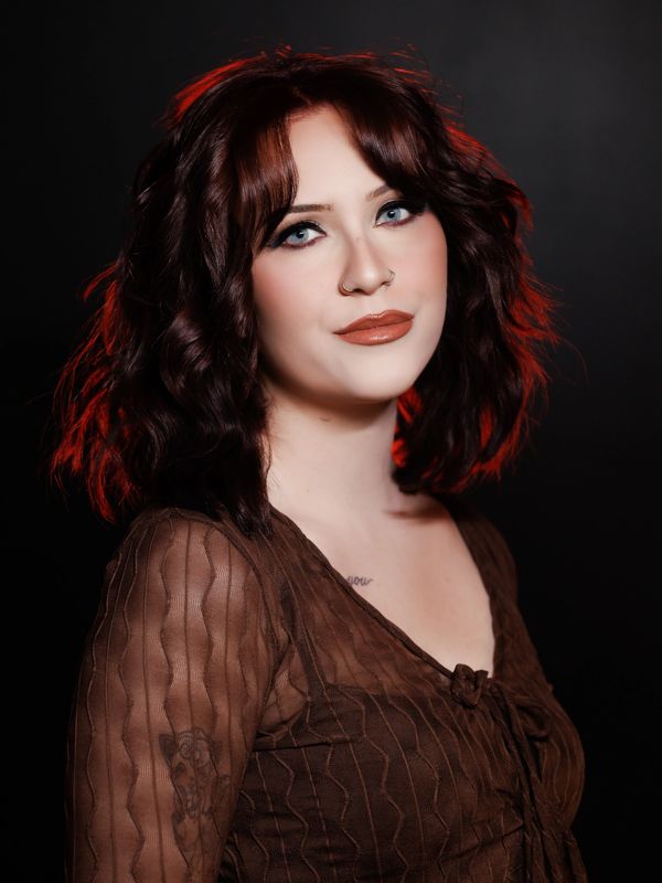Woman with red-tinted wavy hair and brown dress.
