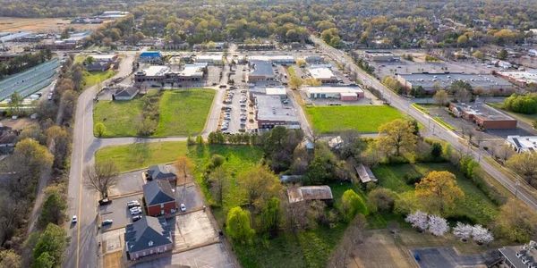 Aerial view of a suburban area with greenery and commercial buildings.