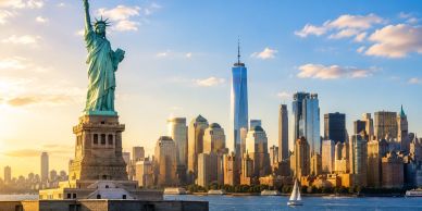 Statue of Liberty with Manhattan skyline at sunset.