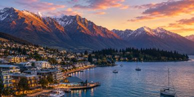 Sunset view of a lakeside town with mountains.