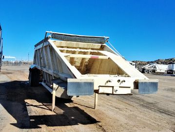 Large industrial dumping trailer under clear blue sky.