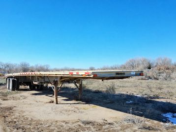 An empty flatbed trailer in a rural area.