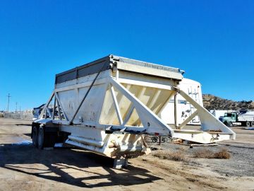 Large industrial hopper trailer under clear blue sky.