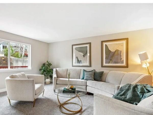 Curved white sofa with two white accent chairs in a living room with sage green pillows