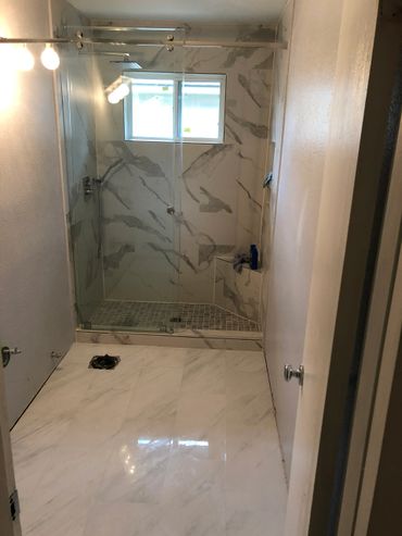 Modern bathroom with marble tiles and glass shower enclosure.