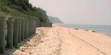Empty sandy beach with wooden posts along the side.