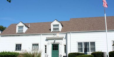 White house with dormer windows and green door under a clear sky.