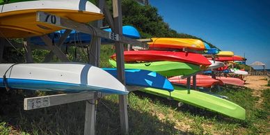 Colorful kayaks stacked on racks by the beach.