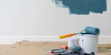 Interior wall painting in progress with professional tools and blue paint.