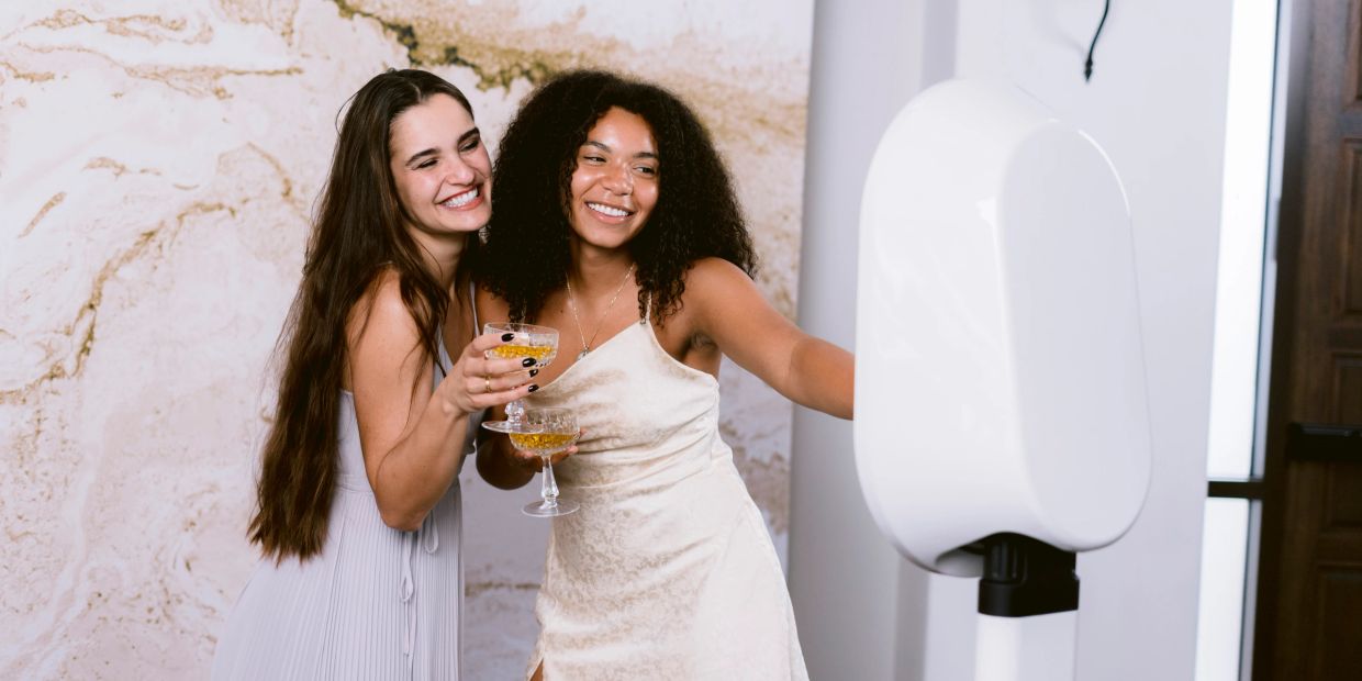 Two women taking a photo at a party with drinks.