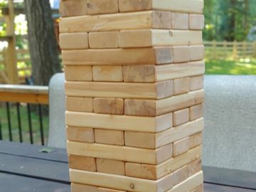 Close-up of a wooden Jenga tower on a table outdoors.