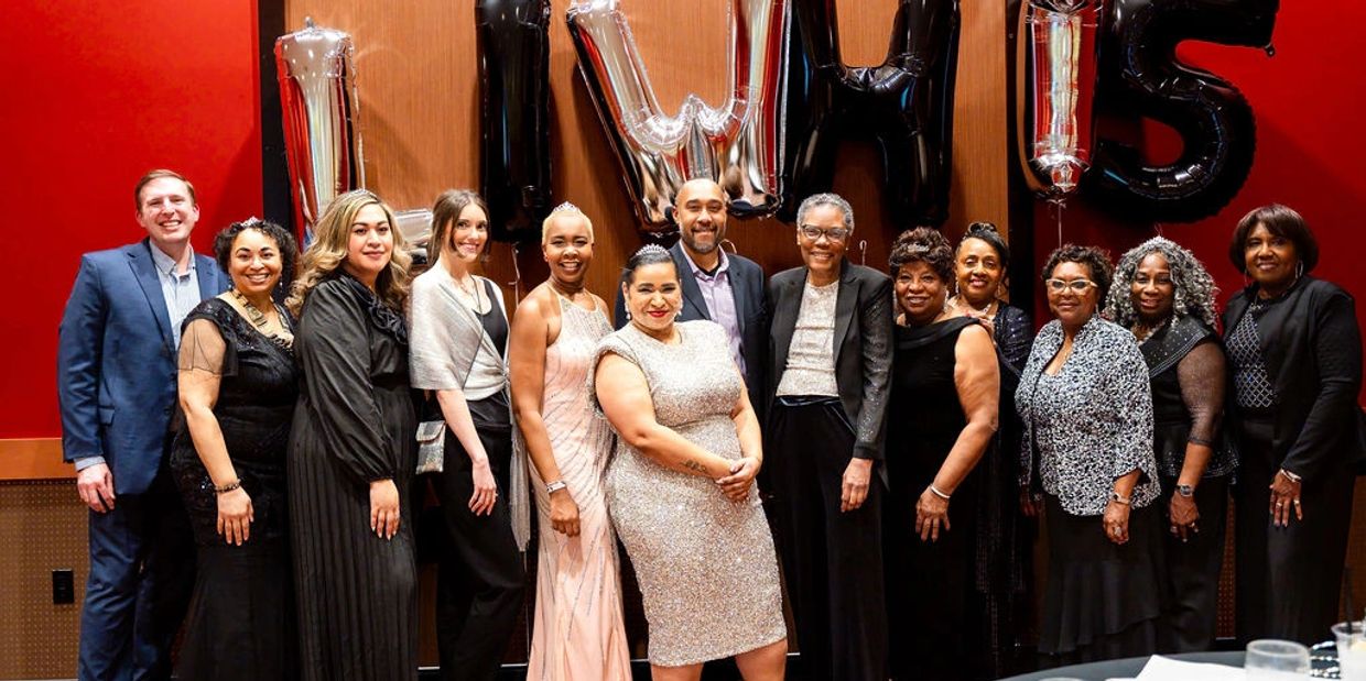 A group of people dressed formally posing with LWHS balloons in the background.