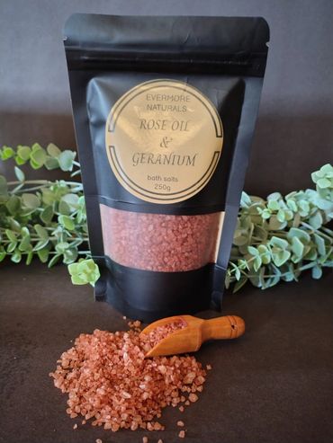 Bag of rose oil and geranium bath salts with a wooden scoop.