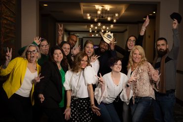 Group of people posing happily indoors with peace signs and smiles.