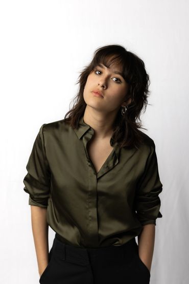 Young woman with dark hair wearing an olive green shirt.