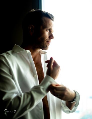 Man in white shirt looking thoughtfully out of window.