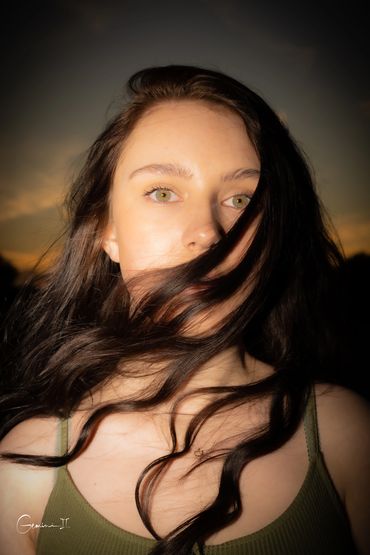 Close-up of a woman with flowing dark hair at sunset.