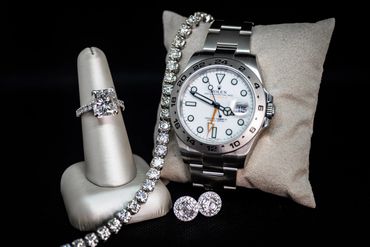 Luxury diamond jewelry and a Rolex watch displayed.