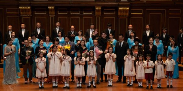 Group photo of performers and children on stage.
