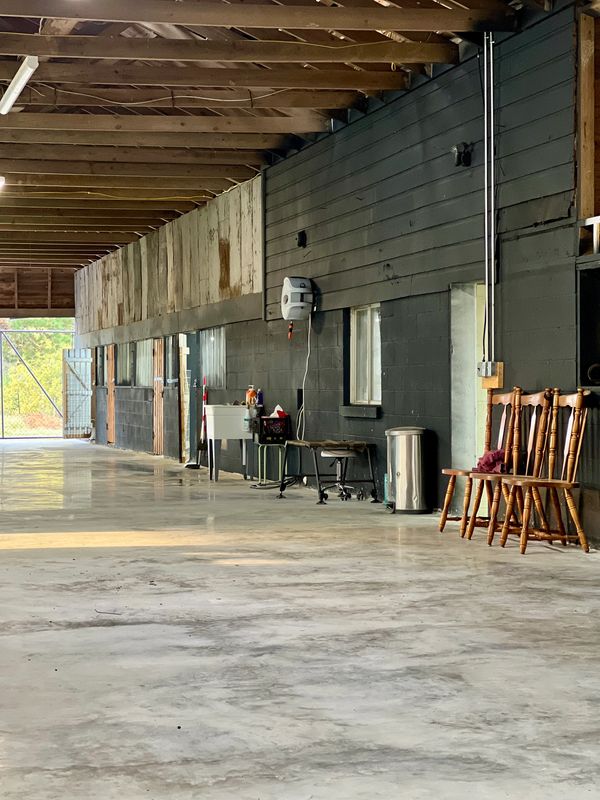 A spacious indoor area with wooden chairs, a sink, and exposed ceiling beams.