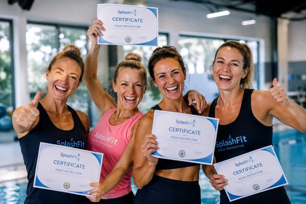 Four women proudly holding Aqua Instructor certificates by a pool.